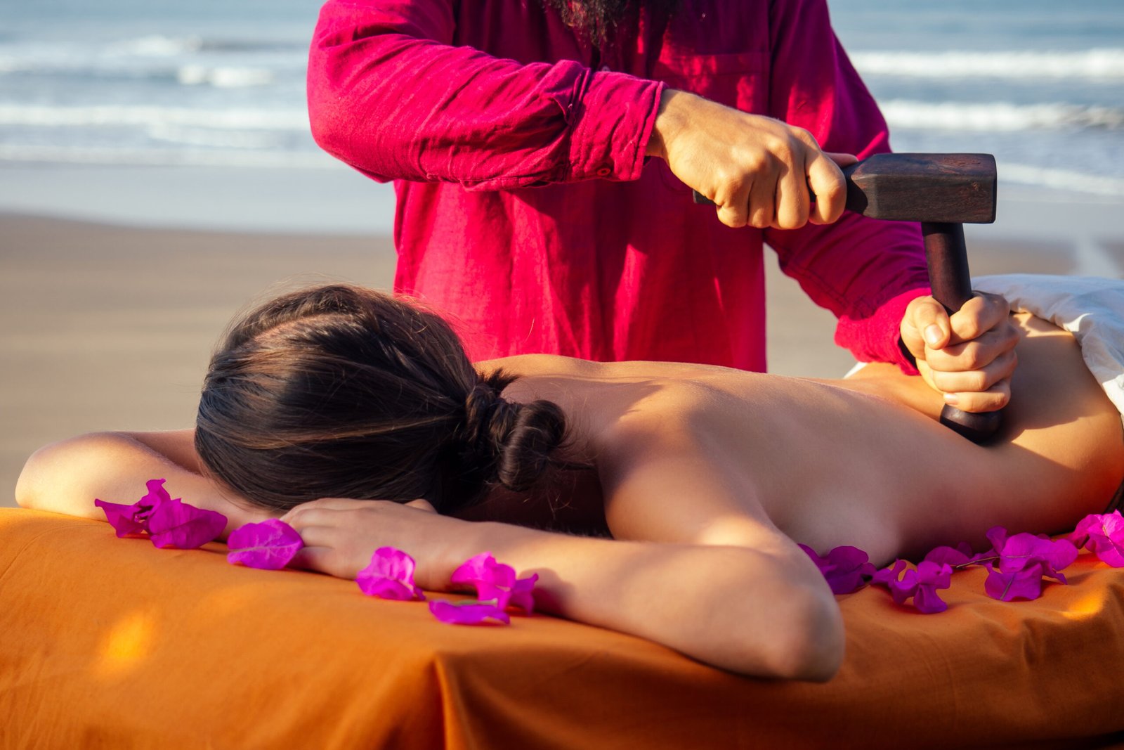 male master makes Thai massage Tok-sen spa therapy physiology by the sea ocean beach.Beautiful woman having a relaxing thai back massage with set for massage toksen,Body care relaxation resort